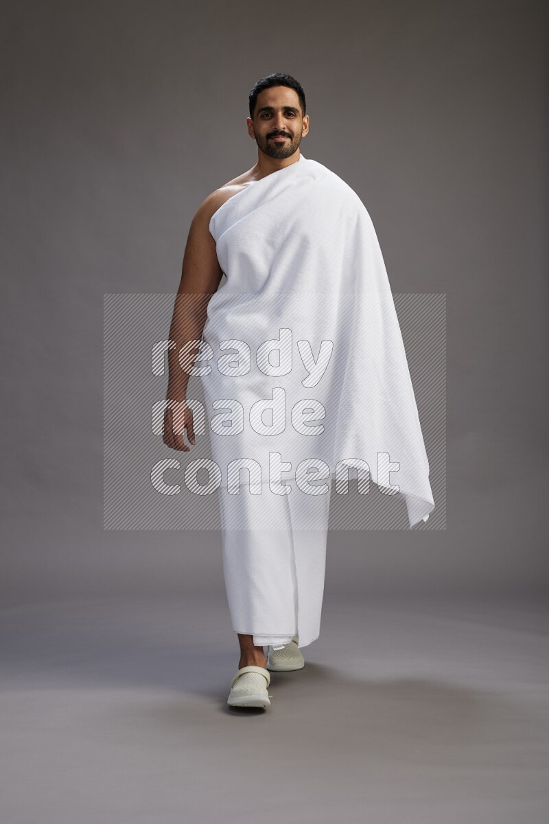 A man wearing Ehram Standing Interacting with the camera on gray background