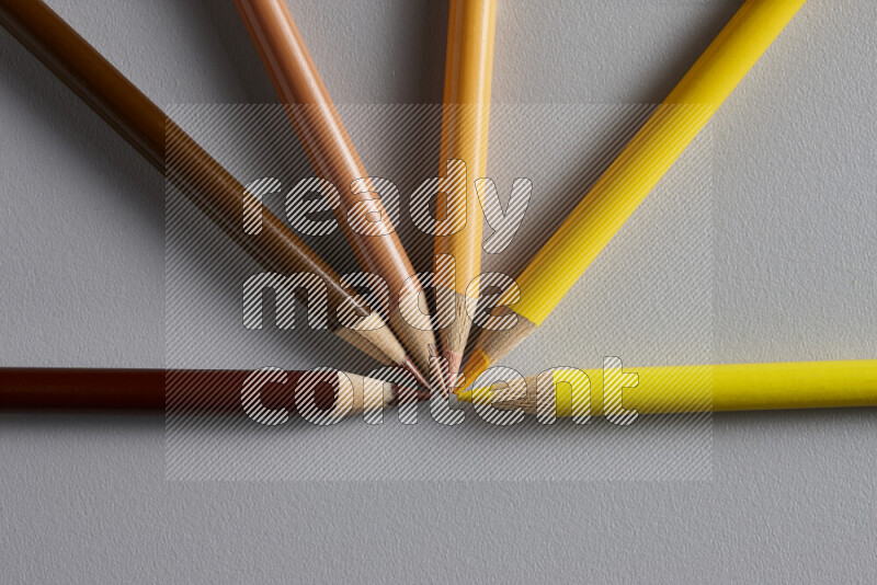 An arrangement of colored pencils in different colors on grey background