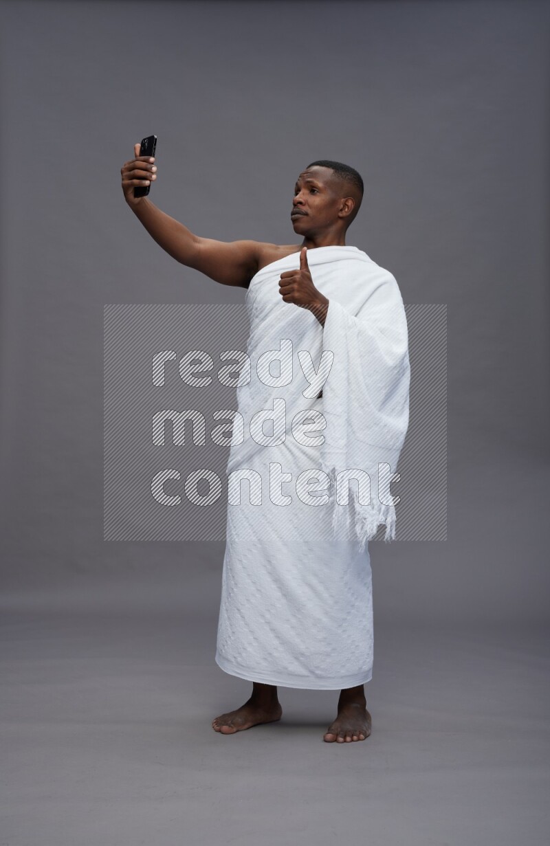 A man wearing Ehram Standing taking selfie on gray background