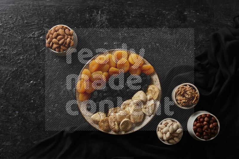 Dried fruits in a pottery bowl with nuts in a dark setup