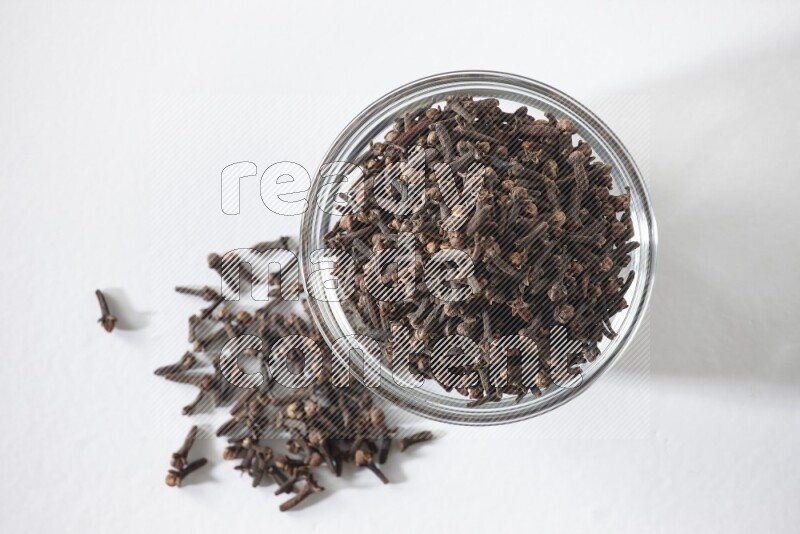 A glass bowl full of cloves on a white flooring