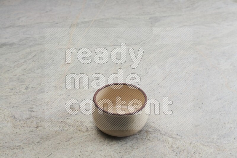 A beige pottery oven bowl on grey marble background