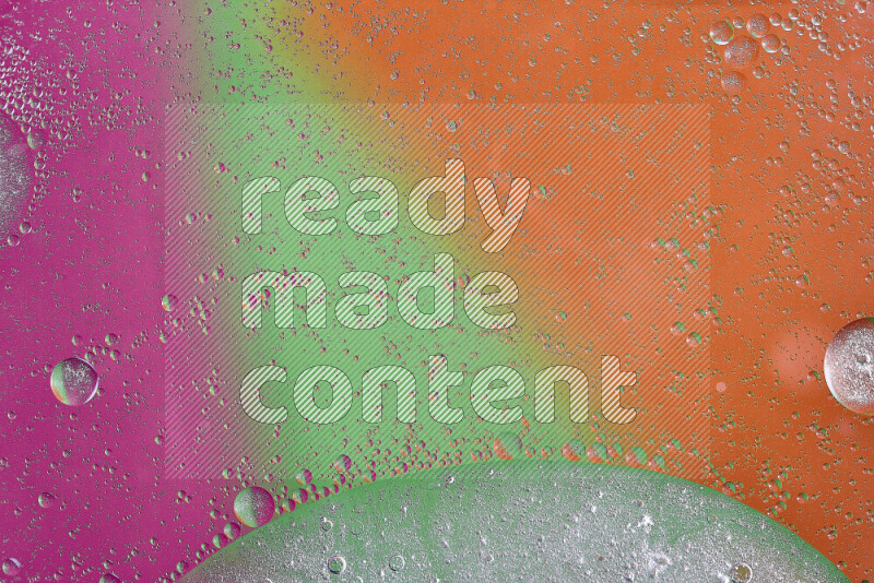 لقطات مقربة لفقاعات من الزيت على سطح الماء باللون البرتقالي والأخضر والوردي