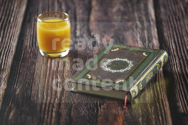 Quran with dates, prayer beads and different drinks all placed on wooden background