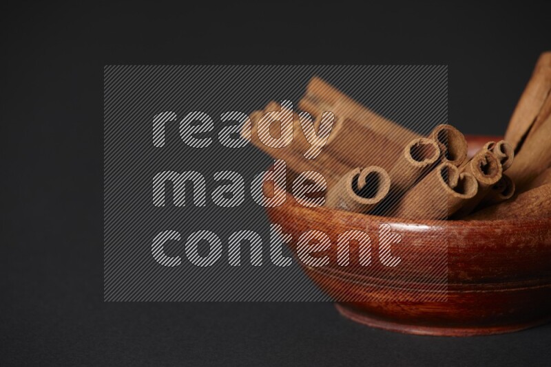 Cinnamon Sticks in a wooden bowl on black background