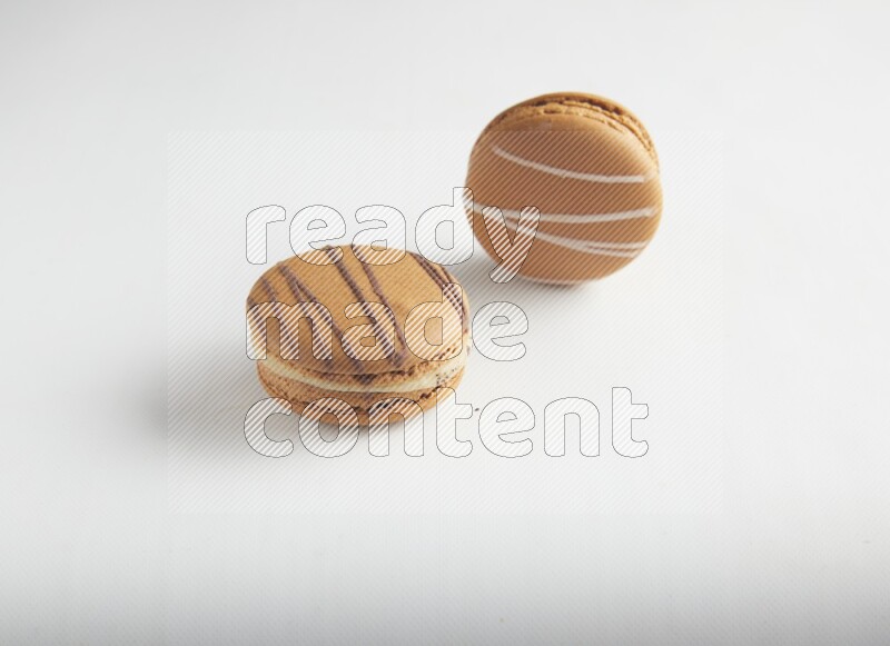 45º Shot of of two assorted Brown Irish Cream, and light brown  Almond Cream macarons on white background