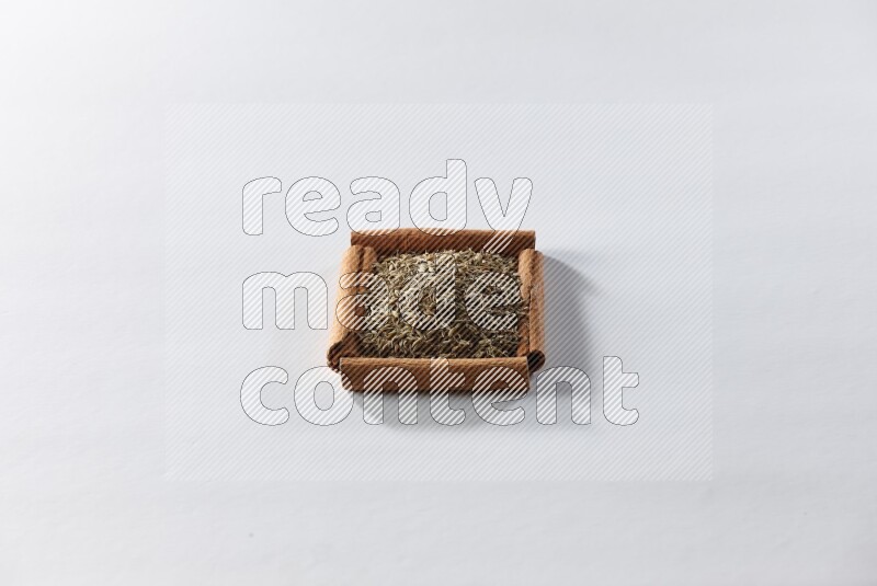 A single square of cinnamon sticks full of cumin on white flooring