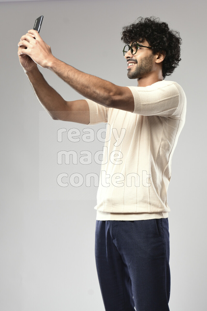 A man wearing casual standing and taking a selfie on white background