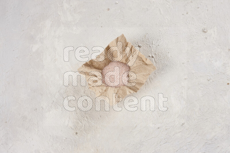 A crumpled piece of paper full of pink himalayan salt on white background
