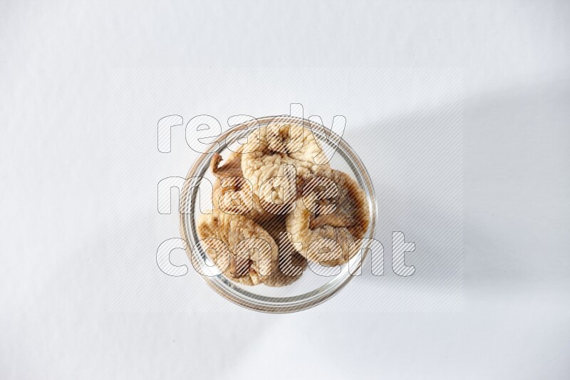 A glass bowl full of dried figs on a white background in different angles