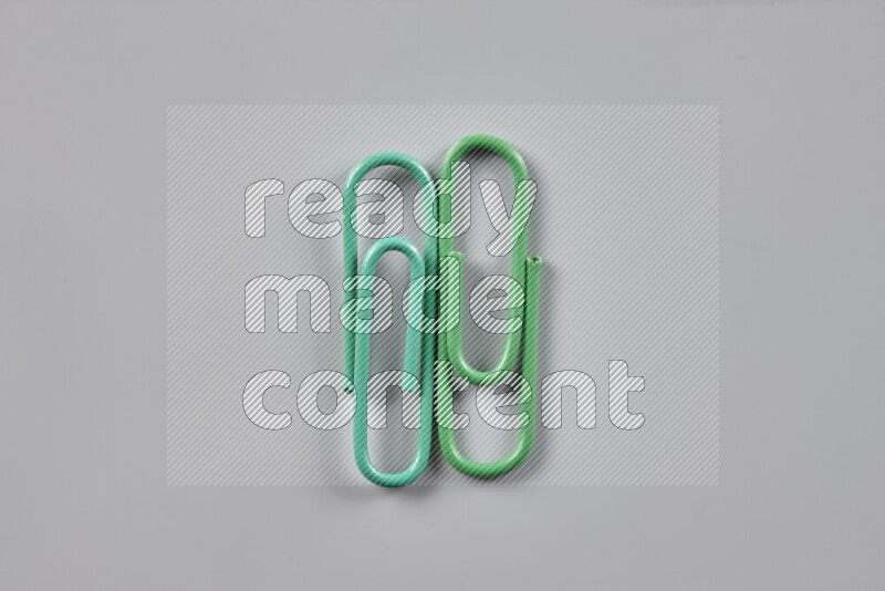 Green paper clips isolated on a grey background