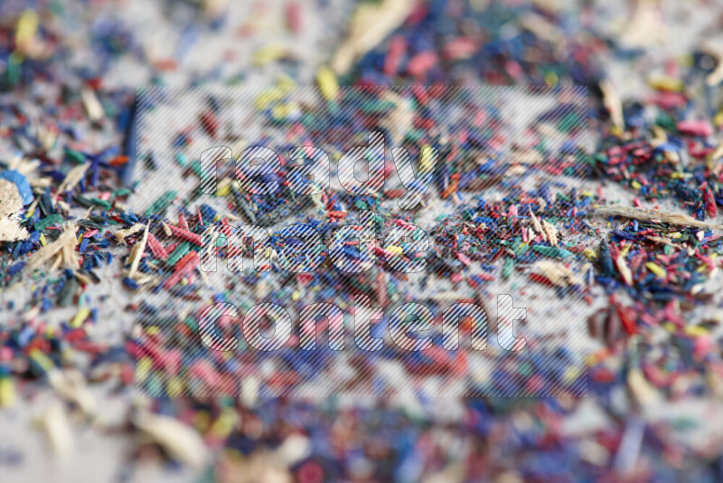 This image showcases a vibrant multicolored pencil shavings scattered on grey background