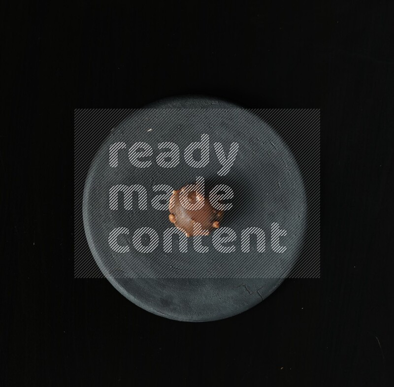 Assorted desserts in a black pottery plate on black background