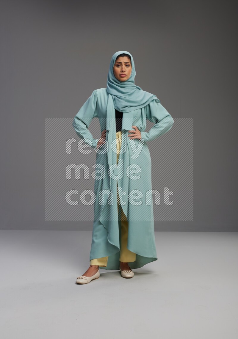 Saudi Woman wearing Abaya standing interacting with the camera on Gray background