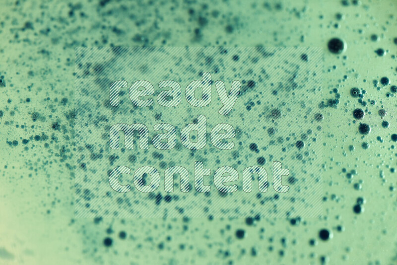 لقطات مقربة لقطرات ألوان مائية خضراء على سطح الزيت على خلفية خضراء