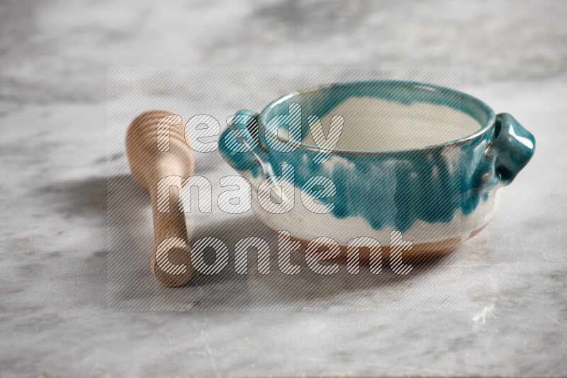 Multicolored pottery bowl with wooden honey dipper on the side on grey marble background