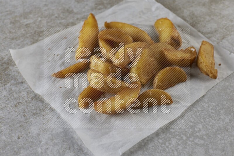 wedges potato on parchment paper on grey textured counter top