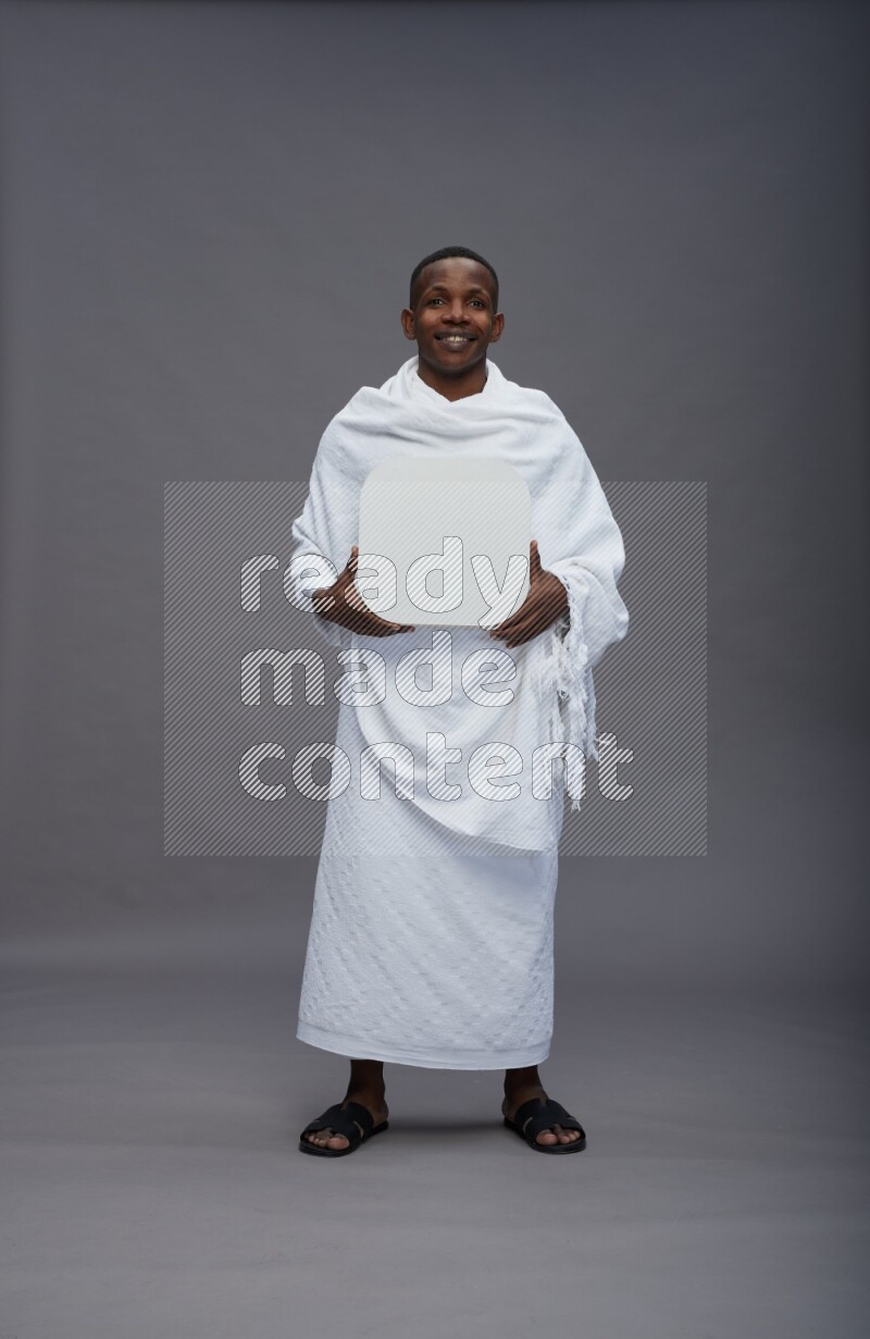 A man wearing Ehram Standing holding social media sign on gray background