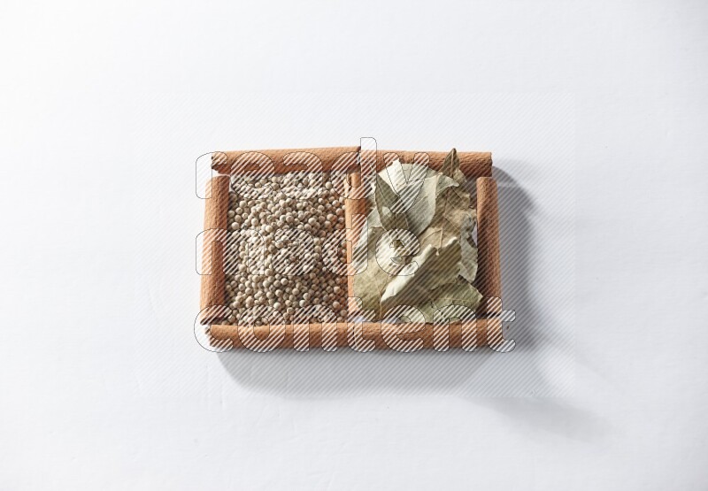 2 squares of cinnamon sticks full of white pepper and bay laurel leaves on white flooring