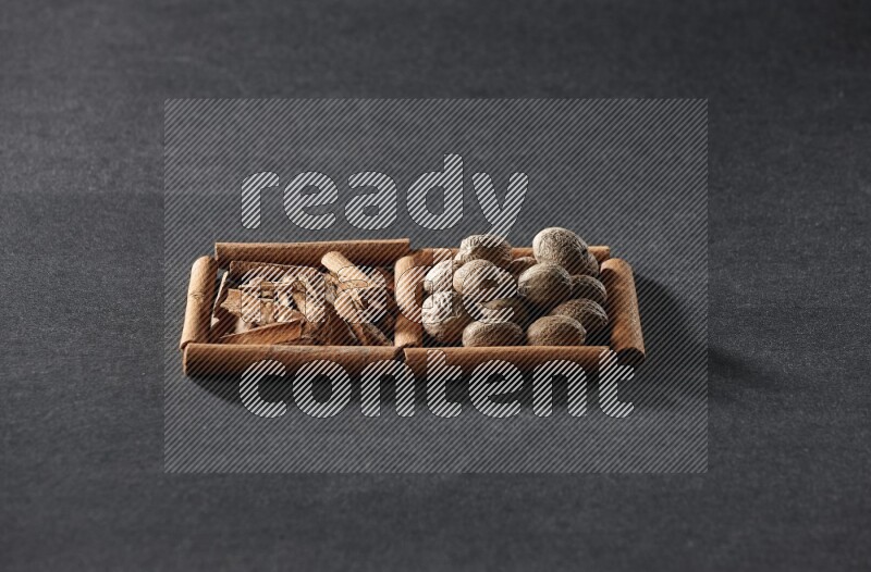 2 squares of cinnamon sticks full of cinnamon and nutmeg on black flooring