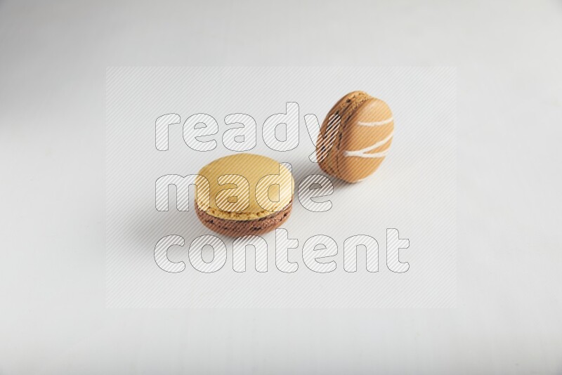 45º Shot of of two assorted Brown Irish Cream, and Yellow, and Brown Chai Latte macarons on white background