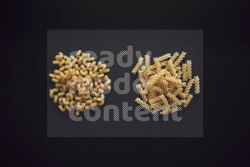 Different pasta types in bunches on black background