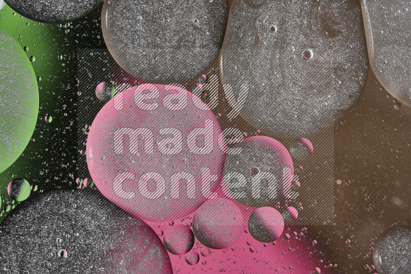 لقطات مقربة لفقاعات من الزيت على سطح الماء باللون البني والأسود والأخضر والوردي