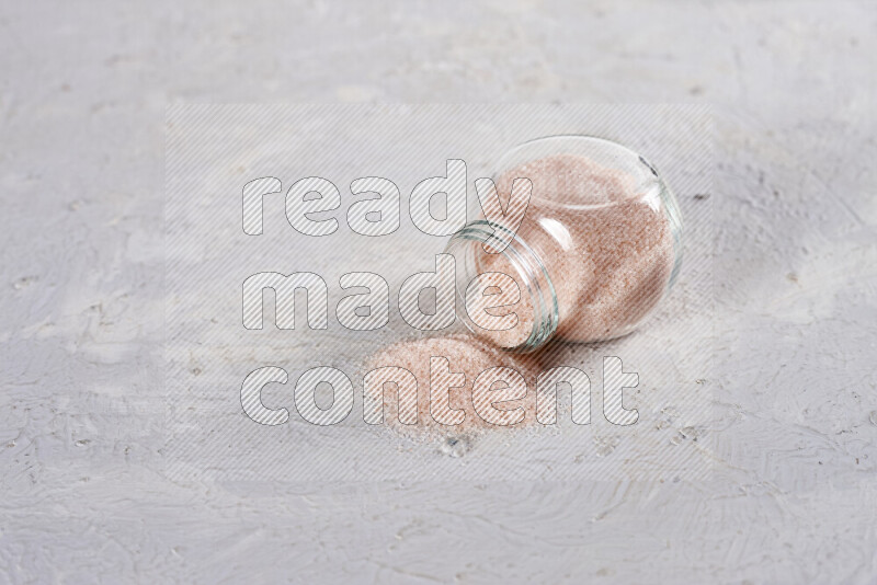 A glass jar full of fine himalayan salt on white background