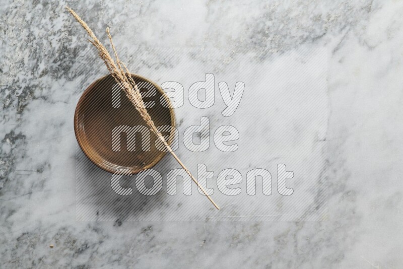 Wheat stalks on multicolored pottery oven plate on grey marble background