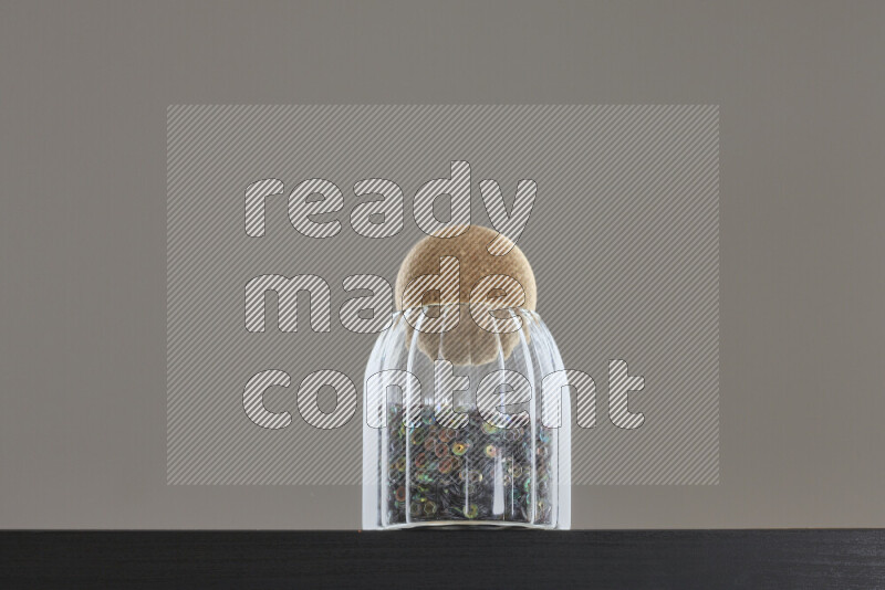 Sequins in a glass jar on black background