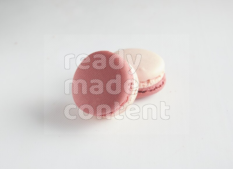 45º Shot of two Pink Litchi Raspberry macarons on white background