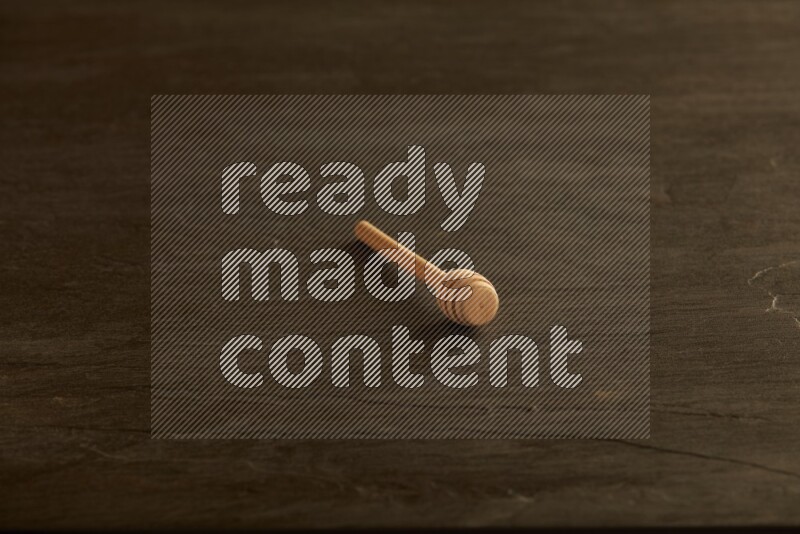Wooden honey dipper on black slate background