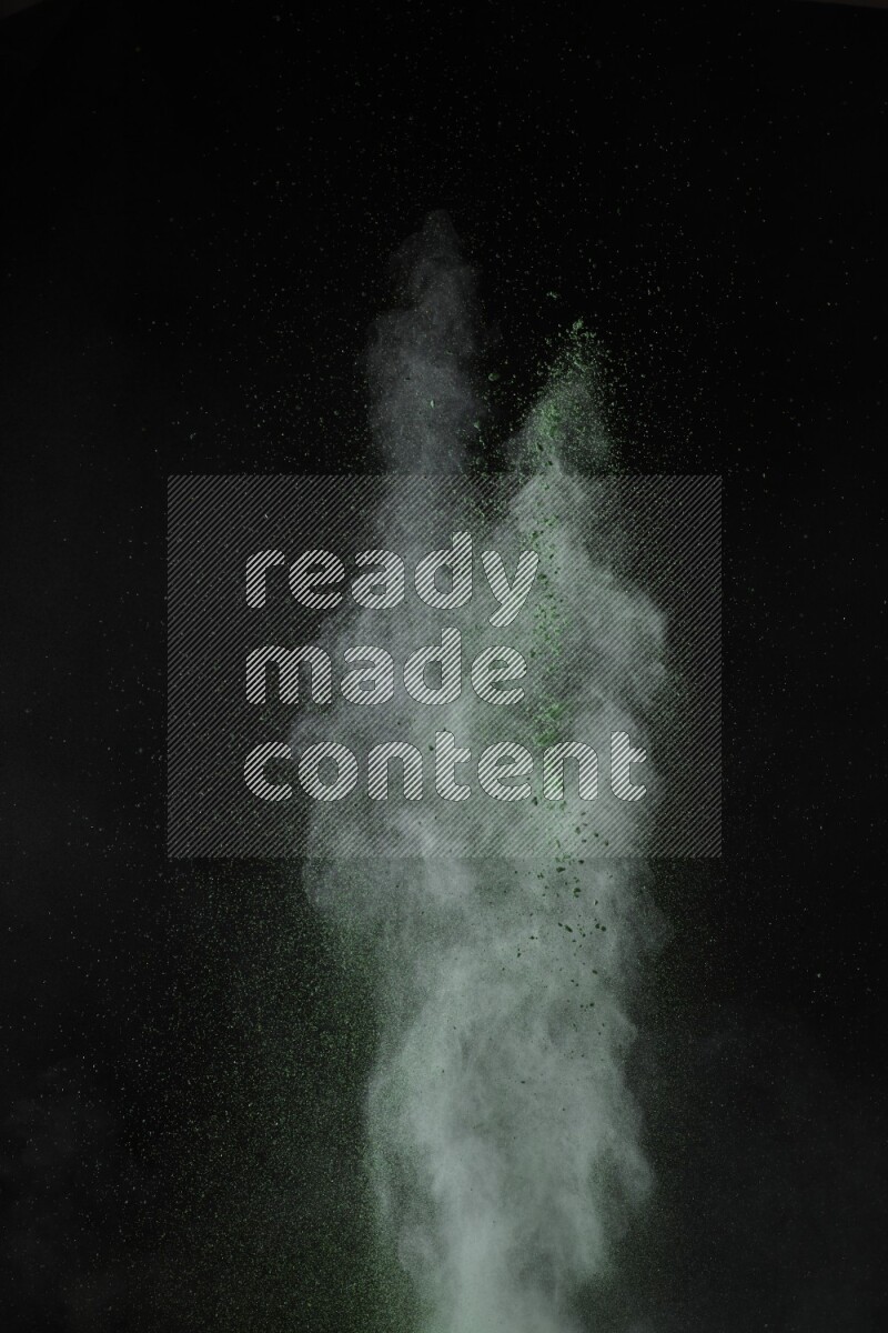 A side view of green powder explosion on black background