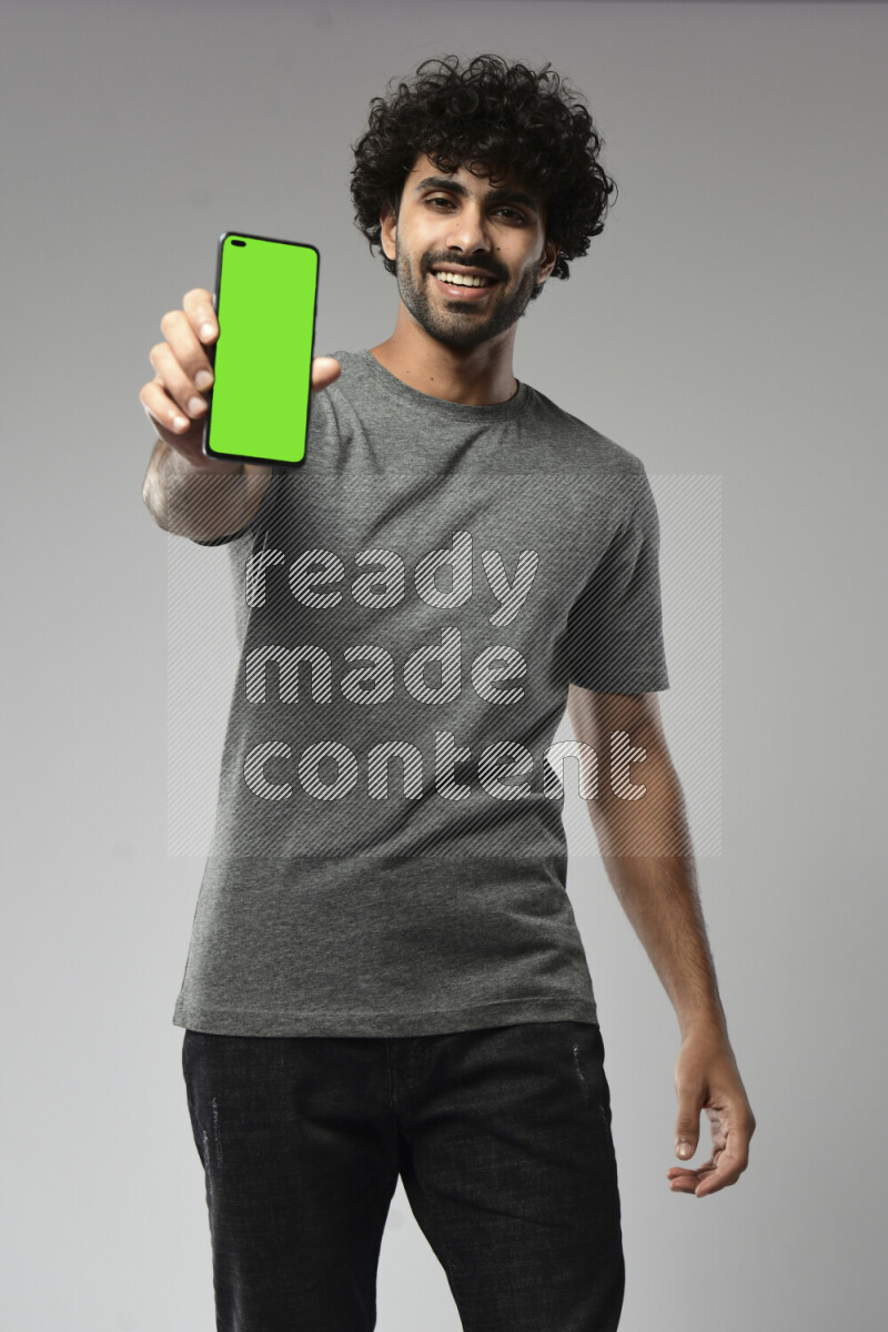 A man wearing casual standing and showing a phone screen on white background