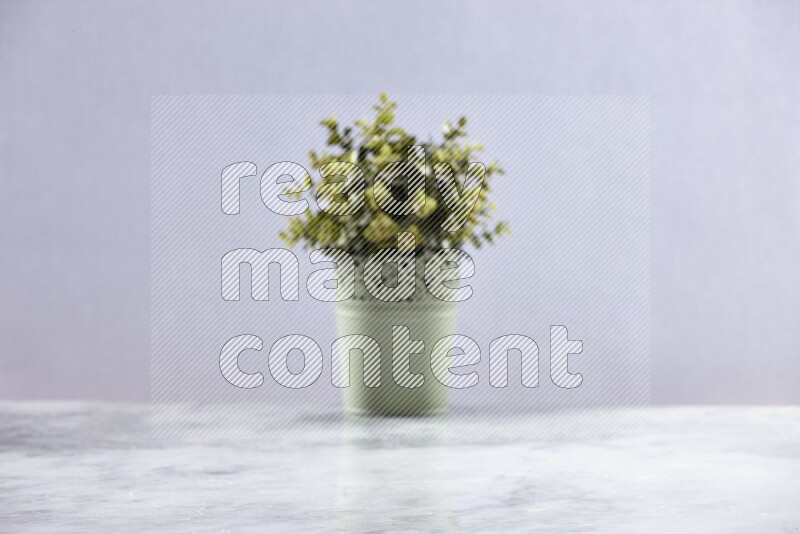 Artificial plant in green decorative pot on grey marble background