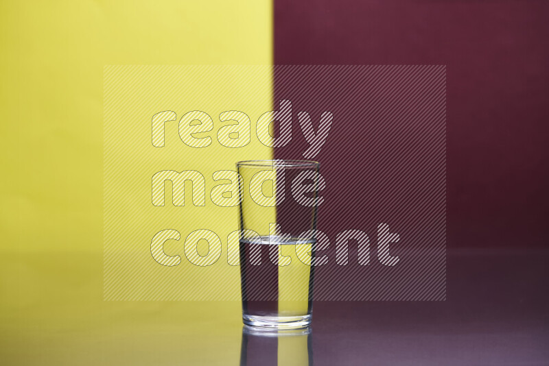 The image features a clear glassware filled with water, set against yellow and dark red background
