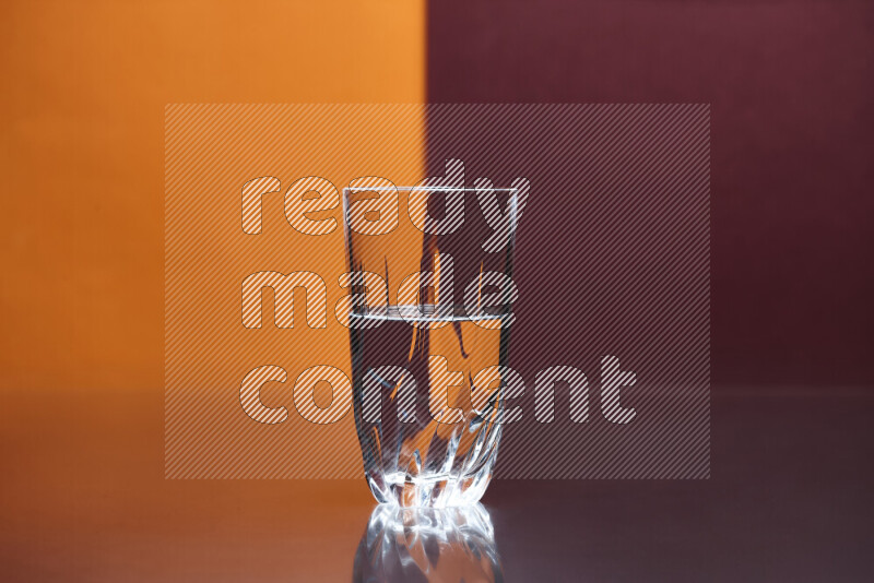 The image features a clear glassware filled with water, set against orange and dark red background