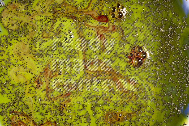 A close-up of sparkling gold glitter scattered on swirling green and red background