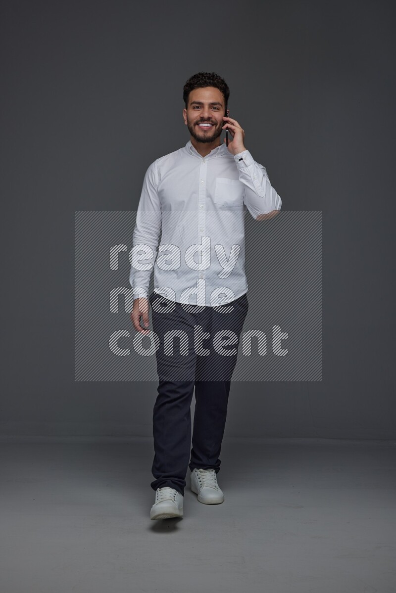 A man wearing smart casual talking in the phone eye level on a gray background