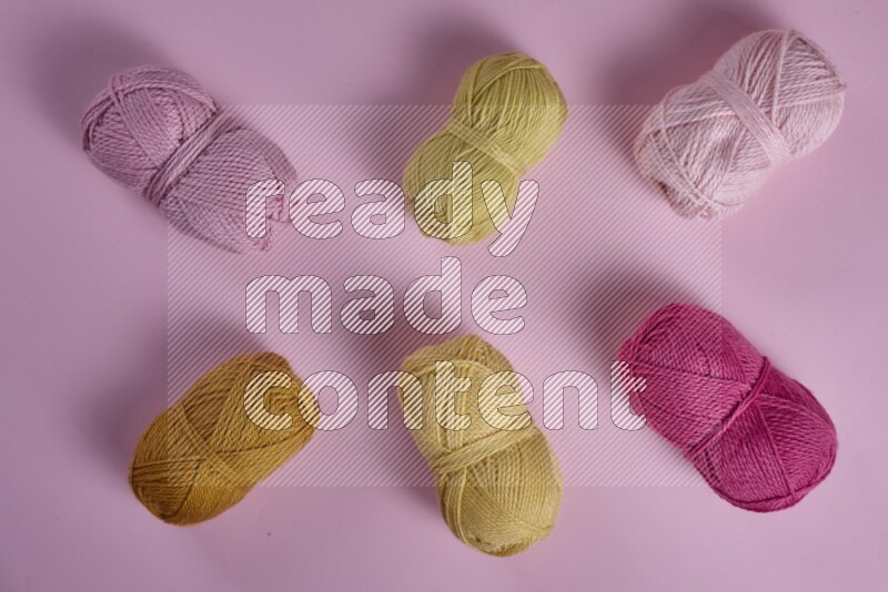 مجموعة من أدوات الخياطة والتفصيل صفراء وزهرية اللون على خلفية زهرية