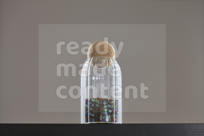 Sequins in a glass jar on black background