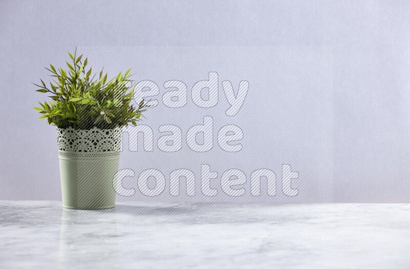 Artificial plant in green decorative pot on grey marble background