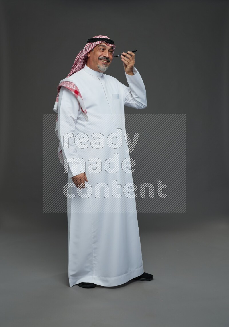 Saudi man with shomag Standing talking on phone on gray background