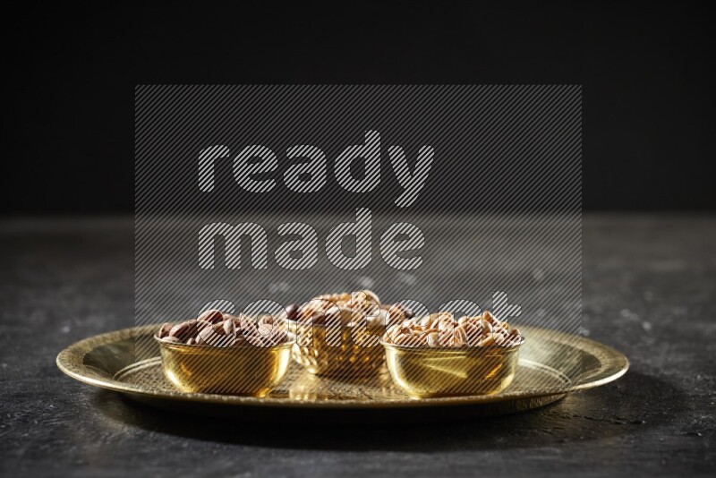 Nuts in metal bowls on a tray in a dark setup