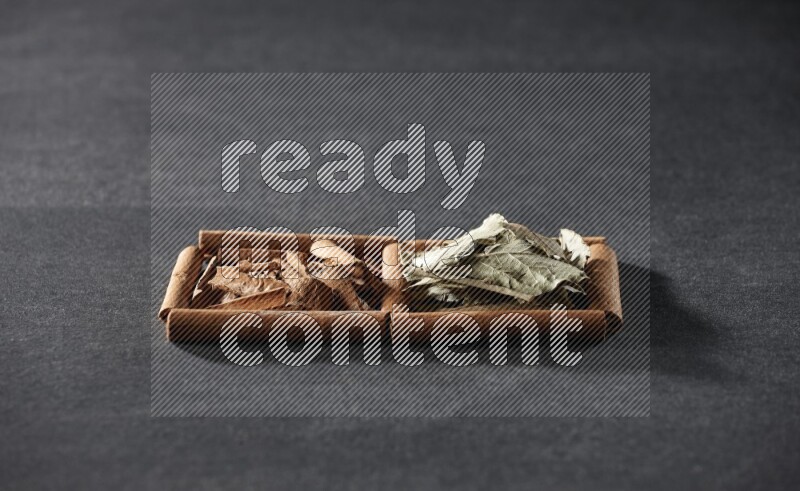 2 squares of cinnamon sticks full of cinnamon and bay laurel leaves on black flooring