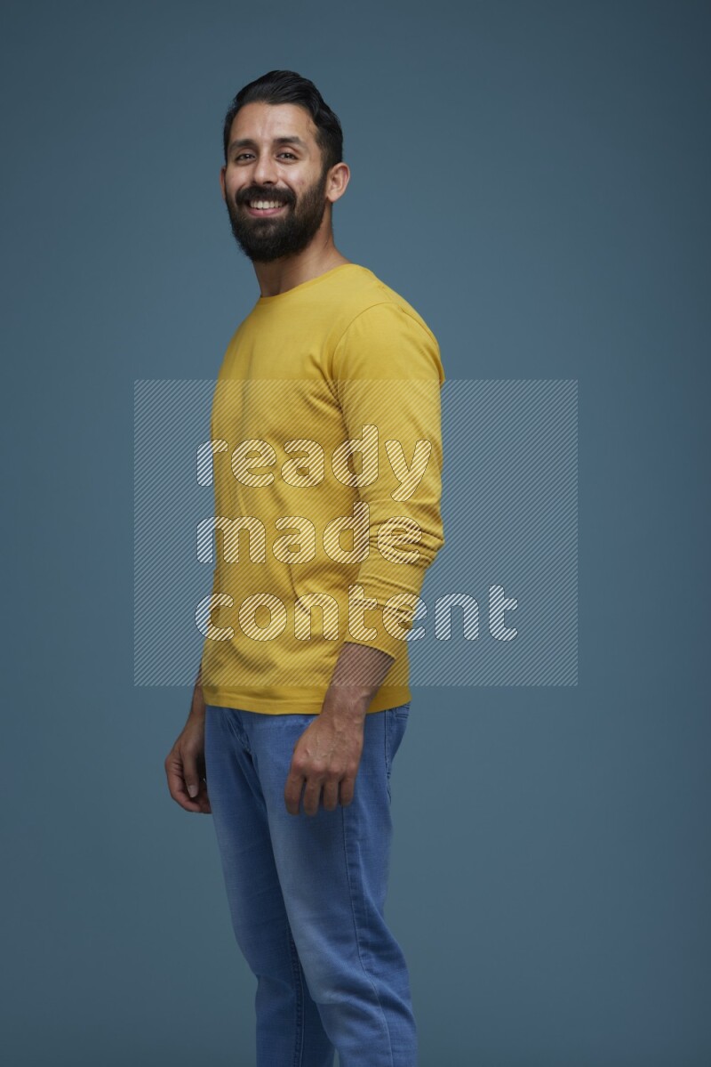 Man posing in a blue background wearing a yellow shirt
