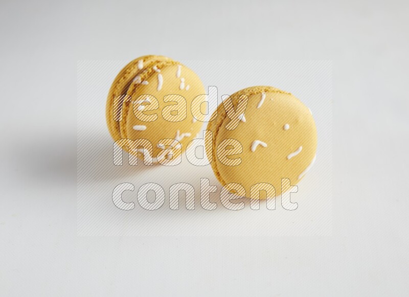 45º Shot of two Yellow Piña Colada macarons on white background