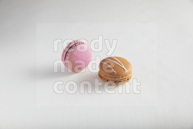 45º Shot of of two assorted Brown Irish Cream, and Purple Strawberry macarons on white background