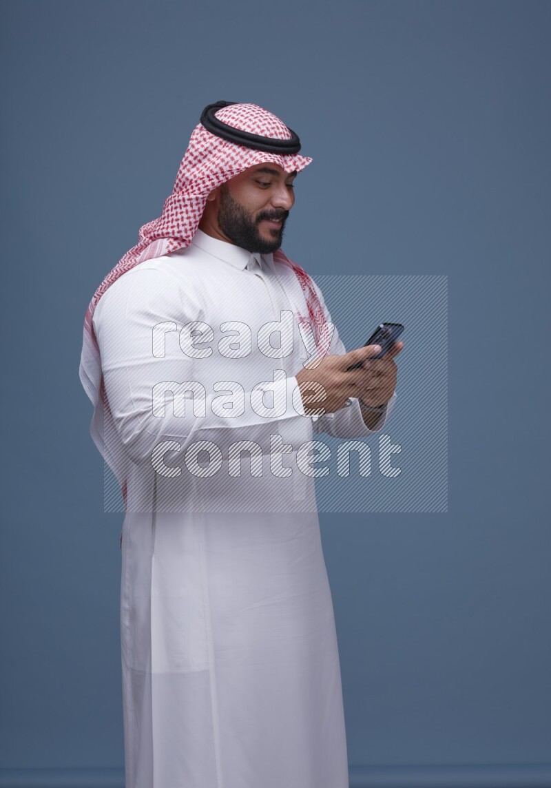 A man Texting on Blue Background wearing Saudi Thob and Shomag