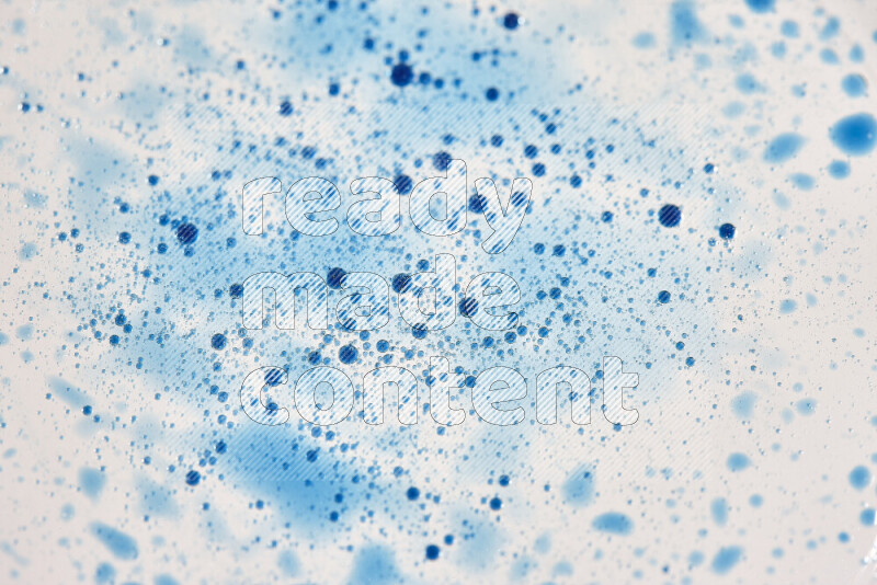 Close-ups of abstract blue watercolor drops on oil Surface on white background